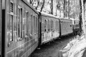 trem de brinquedo movendo-se nas encostas das montanhas, bela vista, uma montanha lateral, um vale lateral movendo-se na ferrovia para a colina, entre a floresta natural verde. trem de brinquedo de kalka para shimla na índia, trem indiano foto