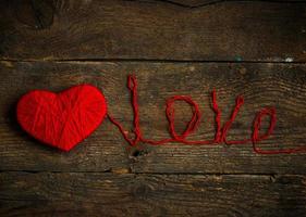 vermelho coração forma com a inscrição amor fez a partir de lã em velho gasto de madeira fundo foto