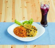 delicioso prato fez do dois tipos do arroz em uma branco prato e uma vidro do suco com gelo foto