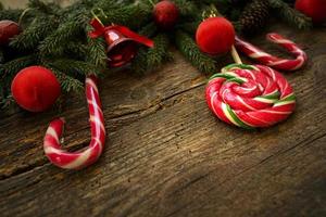 fronteira de Natal com galhos de árvore do abeto, cones, decorações de Natal e pirulito em placas de madeira rústicas foto