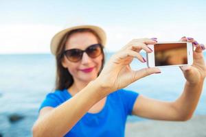 menina dentro a chapéu fazer selfie de a Smartphone em a fundo do mar costa, adriático mar foto