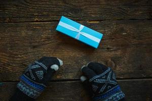 mãos em luvas de inverno com caixa de presente de natal foto