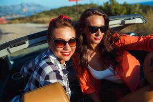 dois jovem feliz meninas tendo Diversão dentro a cabriolet ao ar livre foto