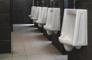 banheiro masculino com mictórios de porcelana branca na fila foto