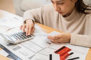 financeiro devo ásia jovem mulher, menina sentado sofrer, estressado e confuso de calcular despesa a partir de fatura ou conta, ter não dinheiro para pagar, hipoteca ou empréstimo. dívida, falência ou falência conceito. foto