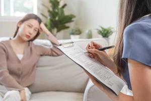 psicologia, depressão. triste, sofrimento ásia jovem mulher consultando com psicólogo, psiquiatra enquanto paciente aconselhamento mental com médico mulher levando notas às clínica. encorajando, terapia. foto