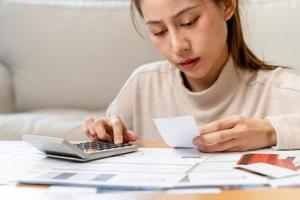 financeiro devo ásia jovem mulher, menina sentado sofrer, estressado e confuso de calcular despesa a partir de fatura ou conta, ter não dinheiro para pagar, hipoteca ou empréstimo. dívida, falência ou falência conceito. foto