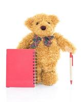 ursinho de pelúcia com caneta e caderno vermelho em branco foto