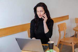 lindo empresária trabalhando em uma computador portátil. fêmea trabalhador autonomo conectando para Internet através da computador. blogueiro ou jornalista escrevendo Novo artigo. foto