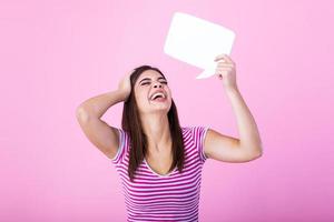 jovem lindo menina segurando uma bolha para texto, isolado em uma Rosa fundo. jovem mulher com sorrir segurando em branco discurso bolha contra fundo foto