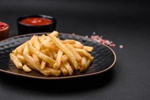 delicioso crocantes francês fritas com sal e especiarias em uma Sombrio concreto fundo foto