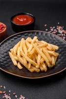 delicioso crocantes francês fritas com sal e especiarias em uma Sombrio concreto fundo foto