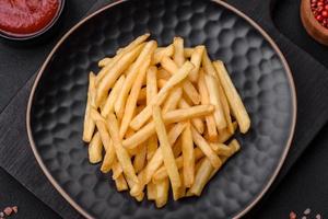 delicioso crocantes francês fritas com sal e especiarias em uma Sombrio concreto fundo foto