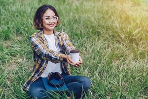 ásia mulher sentado e bebendo café dentro a jardim foto