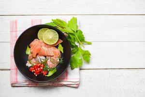 salmão salada - peixe salmão filé em bolw de madeira fundo fechar acima do cru salmão sashimi frutos do mar com limão ervas e especiarias foto