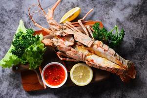 espinhoso lagosta Comida em de madeira corte quadro, fresco lagosta ou Rocha lagosta frutos do mar com erva e especiarias limão coentro salsinha em escuro, lagosta para cozinhando Comida e frutos do mar molho foto