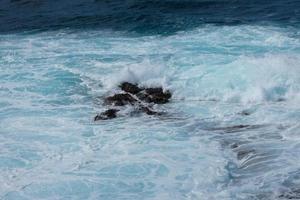 ampla ondas falhando contra a pedras dentro a oceano foto