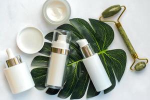 conjunto do cosméticos e jade massageador rolo para pele Cuidado com verde natureza folha. pele Cuidado produtos conceito foto