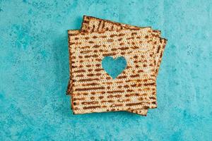 pesach celebração conceito - judaico feriado pesach. matzah quadrados empilhado dentro uma quadrado em azul fundo. coração esculpido dentro matzá. plano deitar foto