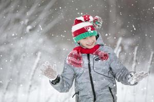 criança dentro inverno dentro a floresta. uma pequeno garoto, uma criança dentro inverno roupas, caminhando debaixo a neve. foto