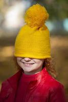 a pequeno menina puxado uma amarelo tricotado chapéu sobre dela olhos. outono tem vir. foto