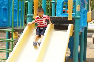 Garoto jogando dentro a Parque infantil dentro a parque foto