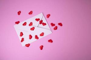 branco envelope com vermelho corações para dia dos namorados dia em uma Rosa fundo. a conceito do uma amor mensagem para marcha 8, mãe dia, do pai dia, família dia. foto