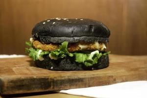 uma Preto hamburguer servido em uma de madeira corte borda é altamente adequado para restaurante cardápio cenário necessidades foto