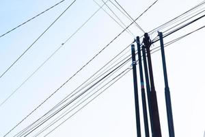 emaranhado fio em elétrico torre contra a azul céu fundo parece tão bagunçado foto