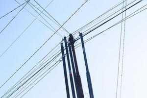 emaranhado fio em elétrico torre contra a azul céu fundo parece tão bagunçado foto