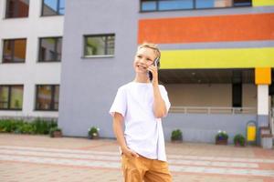 uma criança detém uma telefone dentro dele mãos perto a escola foto