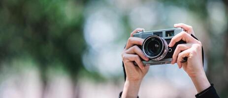 mãos do fêmea profissional fotógrafo leva instantâneos dentro floresta foto