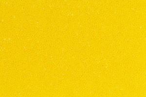 brilhante amarelo cor espuma esponja poroso textura fundo. extremo fechar-se Visão do detalhe abstrato sintético material. horizontal composição foto