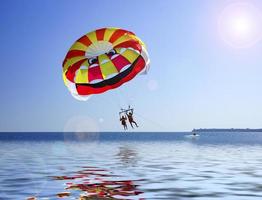 pessoas fazendo parapente em um corpo de água com céu azul claro foto