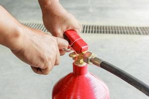 mãos masculinas puxando o pino de segurança do close-up do extintor de incêndio