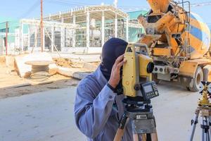 trabalhador topógrafo fazendo medição com equipamento de teodolito no canteiro de obras. foto