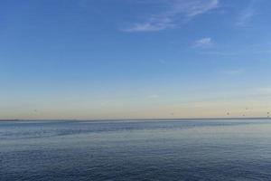 paisagem marinha de um corpo de água com horizonte colorido e céu azul foto