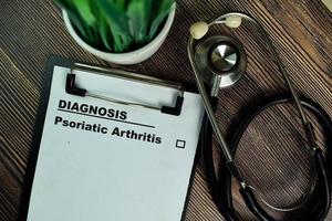 diagnóstico - artrite psoriática escrita em papelada isolada na mesa de madeira foto