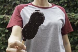 pessoa segurando um palito de sorvete de chocolate foto