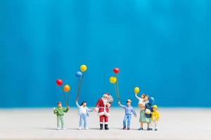 Papai Noel em miniatura e crianças segurando balões, conceito de feliz natal e feliz ano novo foto