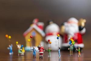 Papai Noel em miniatura e crianças segurando balões, conceito de feliz natal e feliz ano novo foto