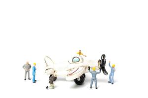 trabalhadores em miniatura consertando um avião de brinquedo em um fundo branco foto