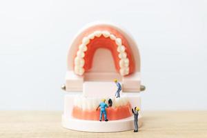 trabalhadores em miniatura consertando um dente, saúde e conceito médico foto