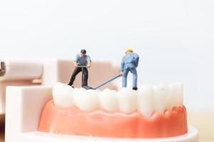 trabalhadores em miniatura consertando um dente, saúde e conceito médico foto