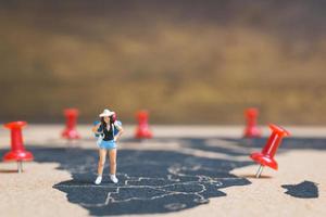 mochileiro em miniatura caminhando em um mapa-múndi, conceito de turismo e viagens foto