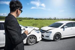 agente de seguros examinando um acidente de carro foto