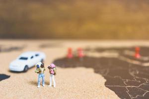 viajantes em miniatura caminhando em um mapa-múndi, viajando e explorando o conceito do mundo foto