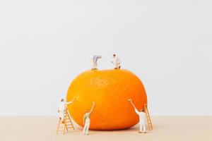 trabalhadores em miniatura pintando em uma laranja
