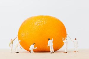 trabalhadores em miniatura pintando em uma laranja foto