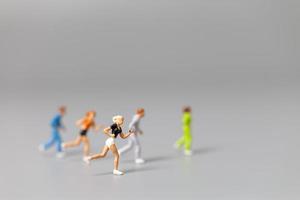 pessoas em miniatura correndo em um fundo cinza foto